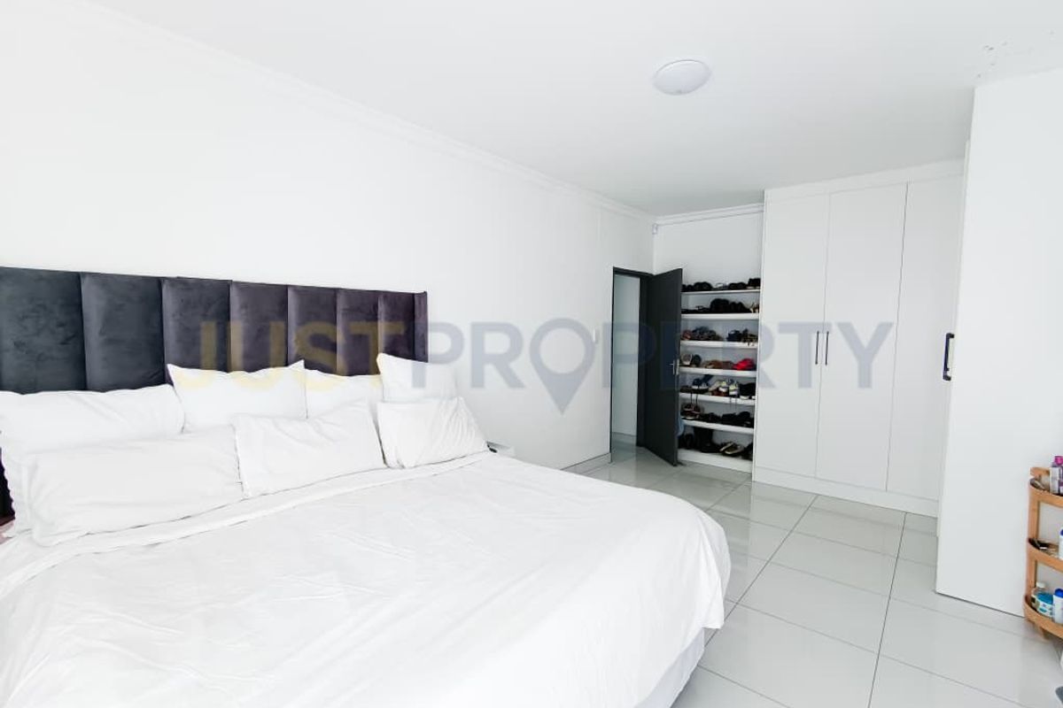 Spacious bedroom featuring neutral tiled flooring, ample built-in cupboard storage, and a clean, minimalist aesthetic.