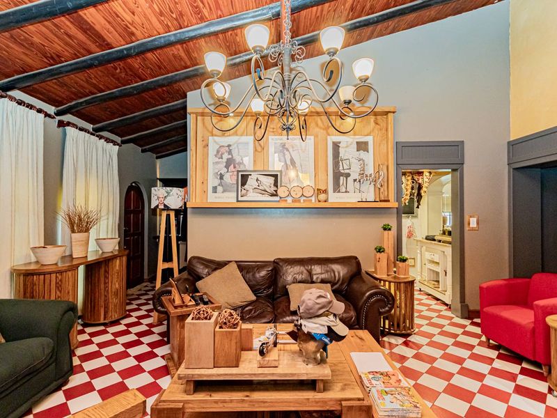 A living room featuring a vaulted timber ceiling, distinctive red and white checkerboard tile flooring, and a central built-in wooden mantle.
