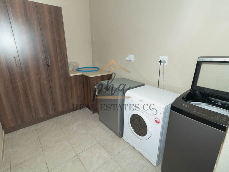 Functional laundry area featuring built-in cabinetry and tiled flooring, providing dedicated space for washing appliances and storage.