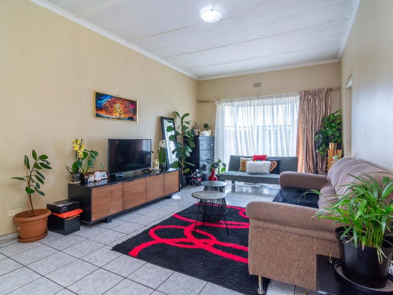 A functional living room featuring tiled flooring and a ceiling vent, offering a neutral base for potential interior updates.