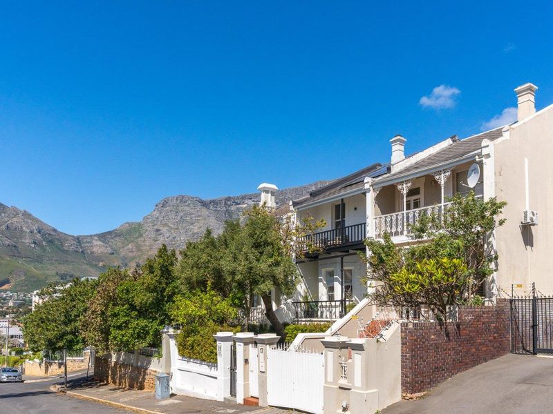 A charming double-story residential property featuring a classic wrought iron balcony, secure boundary walling, and stunning mountain views in a desirable neighborhood setting.