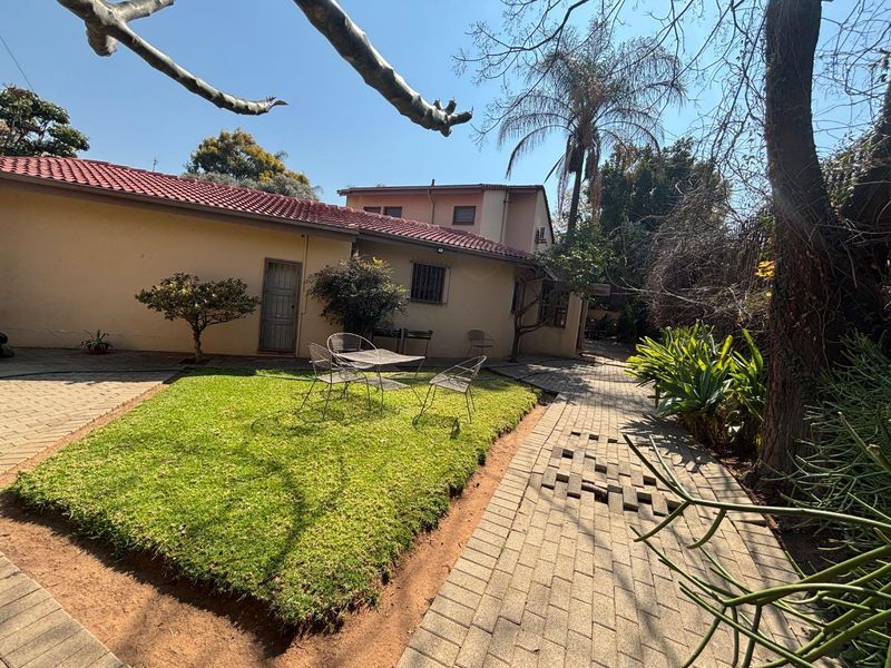 Rear exterior view of the townhouse featuring a paved courtyard area, small lawn, and tiled roof structure.