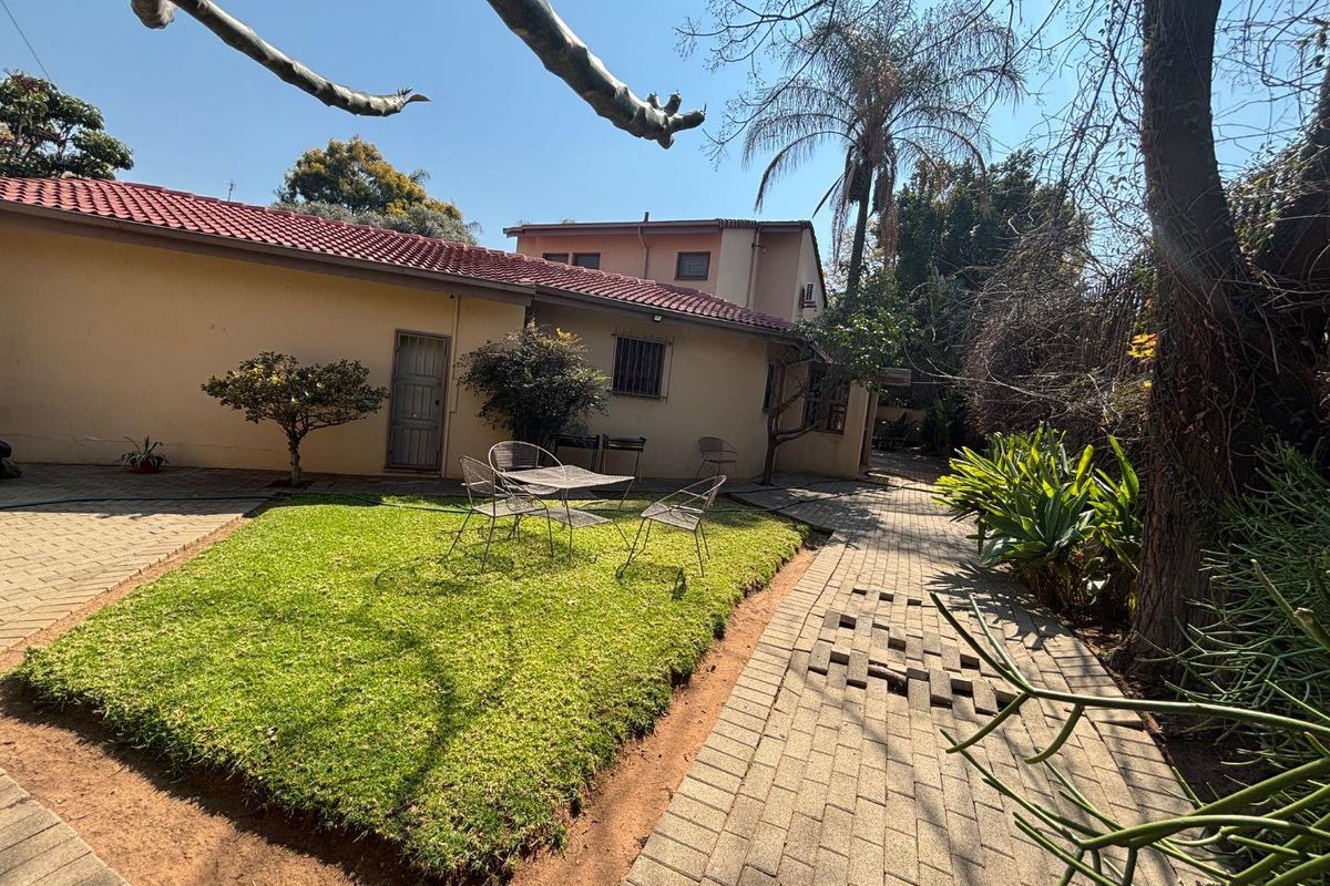 Rear exterior view of the townhouse featuring a paved courtyard area, small lawn, and tiled roof structure.