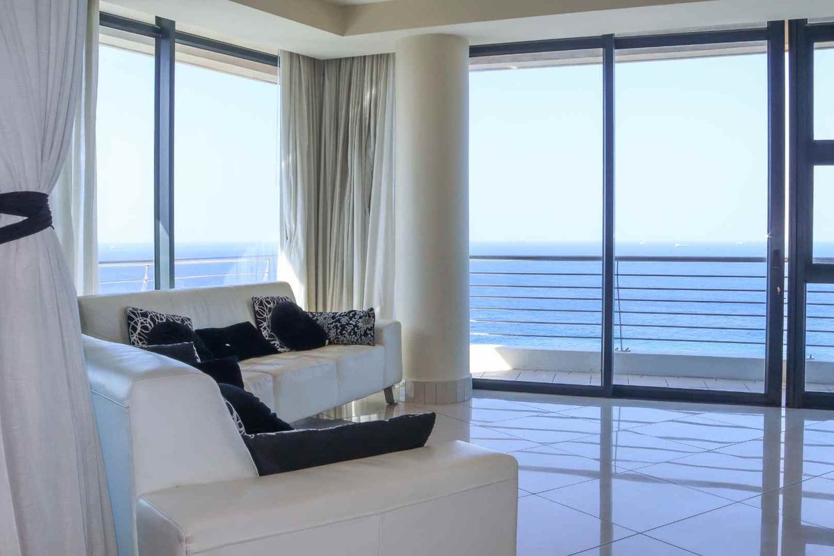 Bright living area featuring floor-to-ceiling glass sliding doors that open onto a balcony with expansive ocean views.