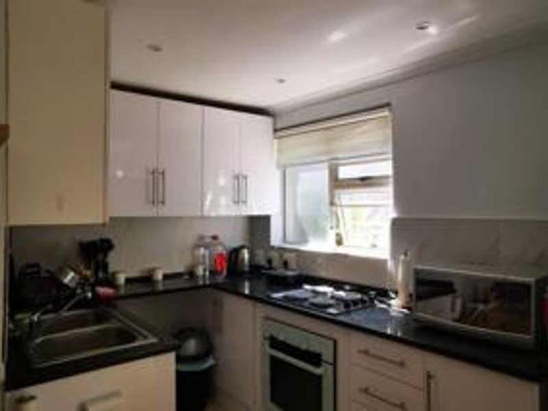A functional kitchen featuring white cabinetry, dark granite countertops, a built-in oven, and a gas hob with recessed lighting.