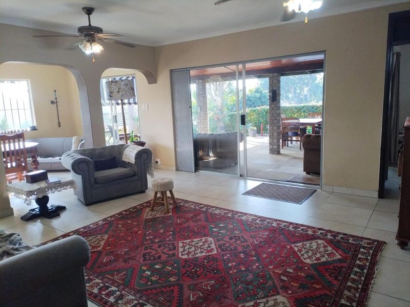 Spacious living area featuring tiled flooring, ceiling fans, and large sliding glass doors that provide seamless access to the outdoor patio.