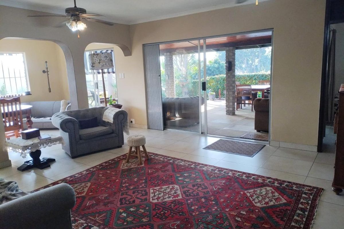 Spacious living area featuring tiled flooring, ceiling fans, and large sliding glass doors that provide seamless access to the outdoor patio.
