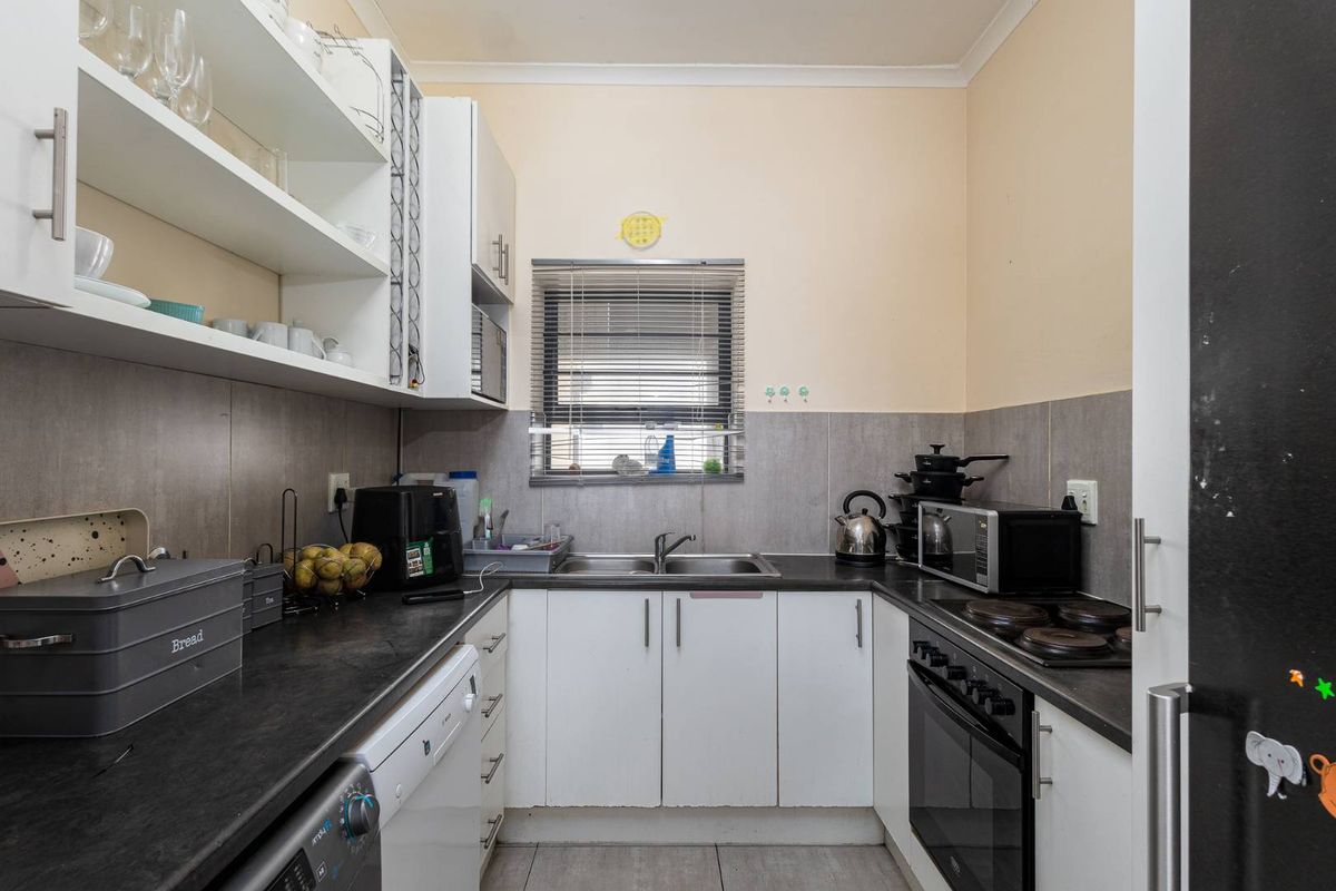 Compact kitchen featuring white cabinetry, dark countertops, a double sink, and a built-in electric oven with hob.
