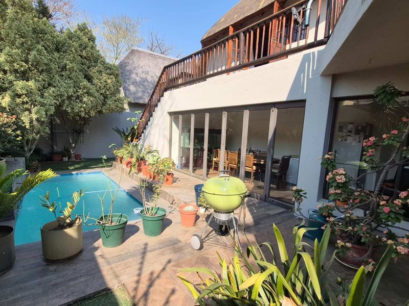 Outdoor pool area featuring a tiled patio, swimming pool, and access to the home via large sliding glass doors with a balcony above.