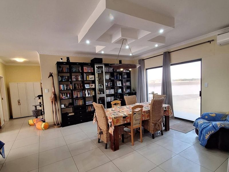 Spacious dining area featuring tiled flooring, a decorative recessed ceiling with integrated lighting, and sliding glass doors leading to the exterior.