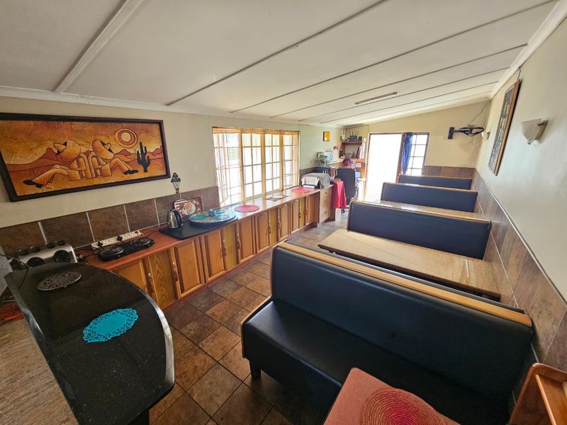A functional kitchen area featuring built-in cabinetry, tiled splashbacks, and integrated bench seating, offering a practical layout for dining and food preparation.