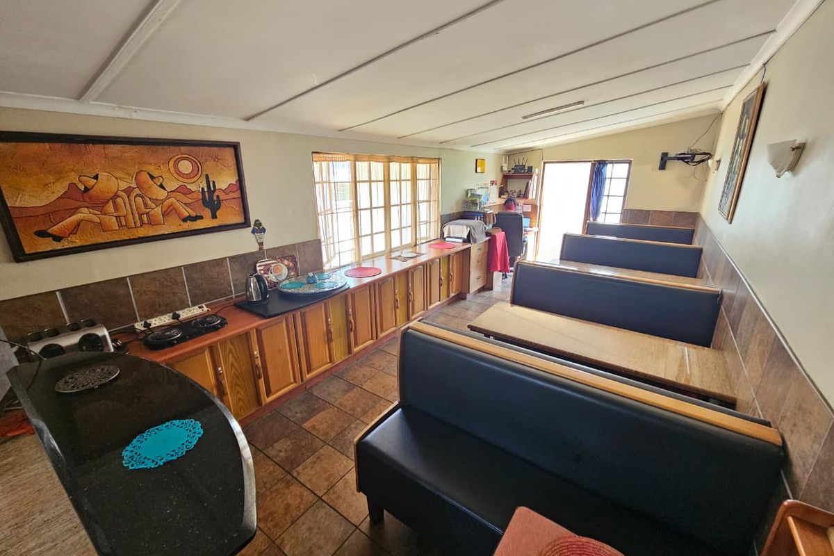 A functional kitchen area featuring built-in cabinetry, tiled splashbacks, and integrated bench seating, offering a practical layout for dining and food preparation.