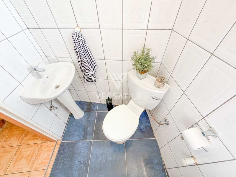 A compact guest bathroom featuring a pedestal basin, toilet, and tiled finishes throughout.