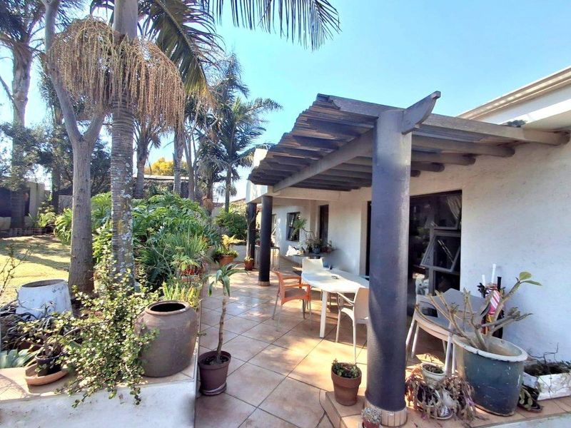 A covered outdoor patio area featuring a timber pergola, tiled flooring, and direct access to the garden.