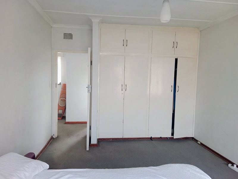 A bedroom featuring built-in cupboards, carpeted flooring, and a neutral color palette, offering a functional space ready for modernization.