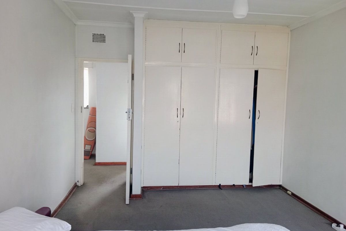 A bedroom featuring built-in cupboards, carpeted flooring, and a neutral color palette, offering a functional space ready for modernization.