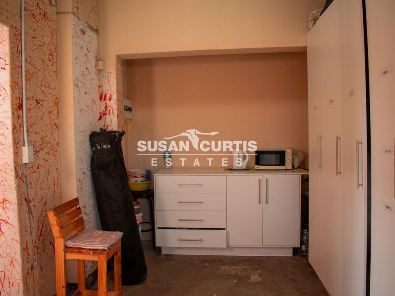 A utility or scullery area featuring built-in cabinetry and storage cupboards, requiring cosmetic updates to the wall finishes and flooring.