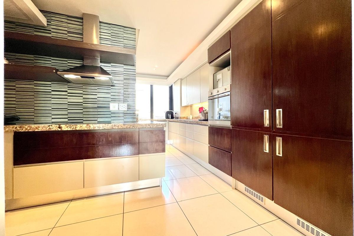 Modern kitchen featuring dark wood and light cabinetry, granite countertops, built-in appliances, and a stylish mosaic tile backsplash with tiled flooring.