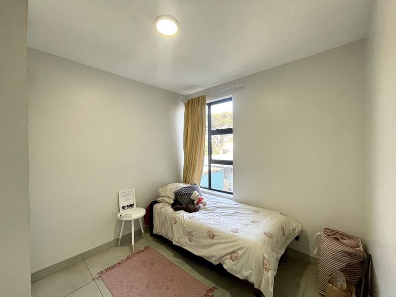 A compact bedroom featuring neutral wall finishes, tiled flooring, and a window providing natural light.
