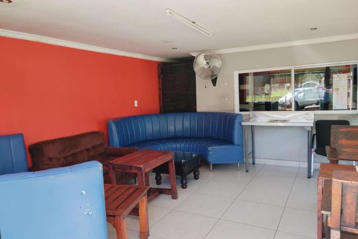 A functional interior space featuring tiled flooring, a prominent red accent wall, and a wall-mounted industrial fan.