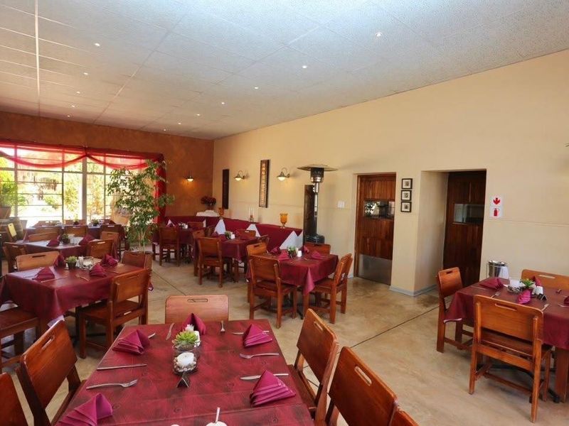 A spacious dining area featuring tiled flooring, recessed ceiling lighting, and wall-mounted light fixtures, suitable for a restaurant or hotel dining setting.