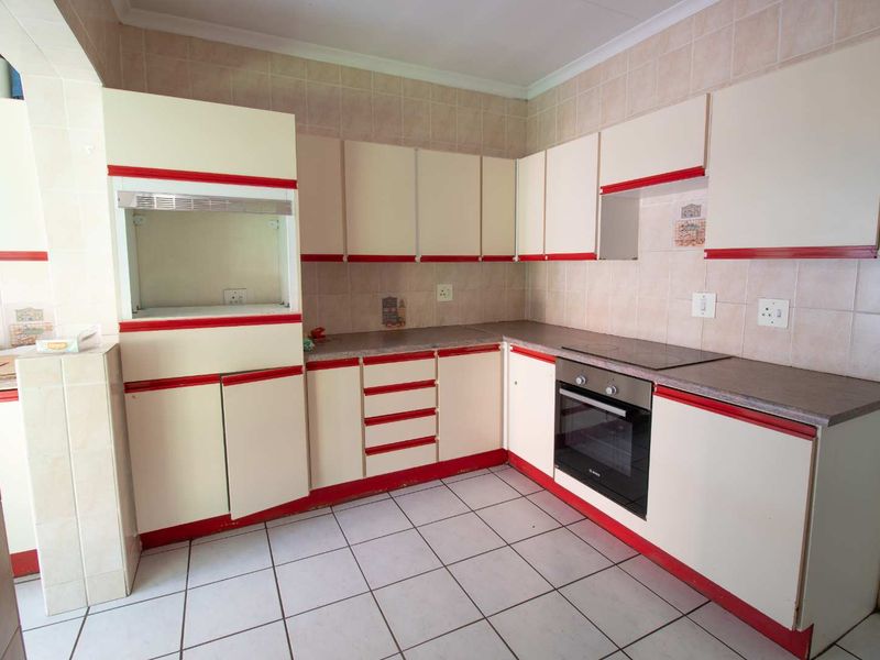 A functional kitchen featuring built-in cabinetry, tiled backsplash, and integrated oven and hob, offering a clean and practical workspace.