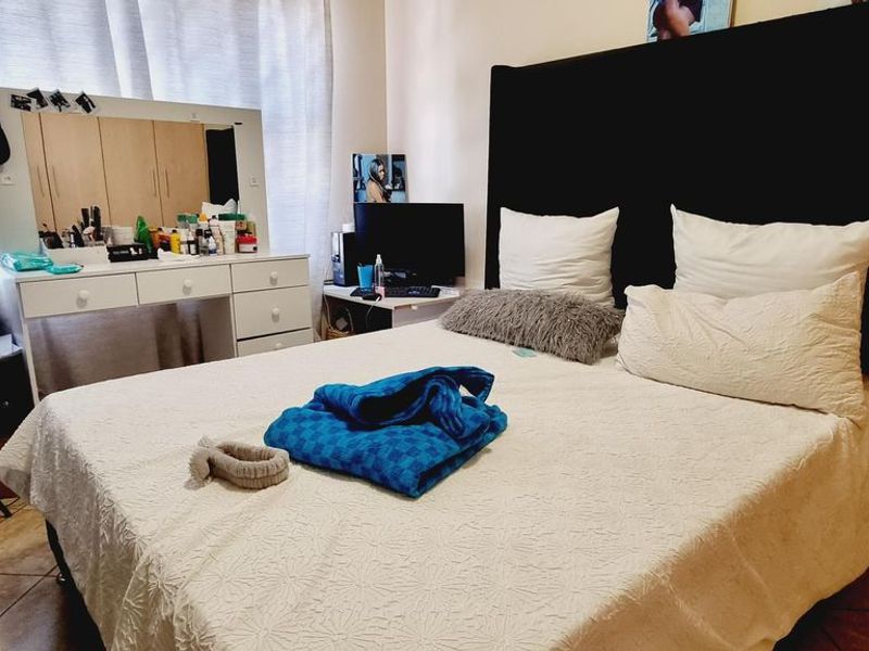 A bedroom featuring tiled flooring and built-in cupboard storage, offering a functional space with neutral wall finishes.