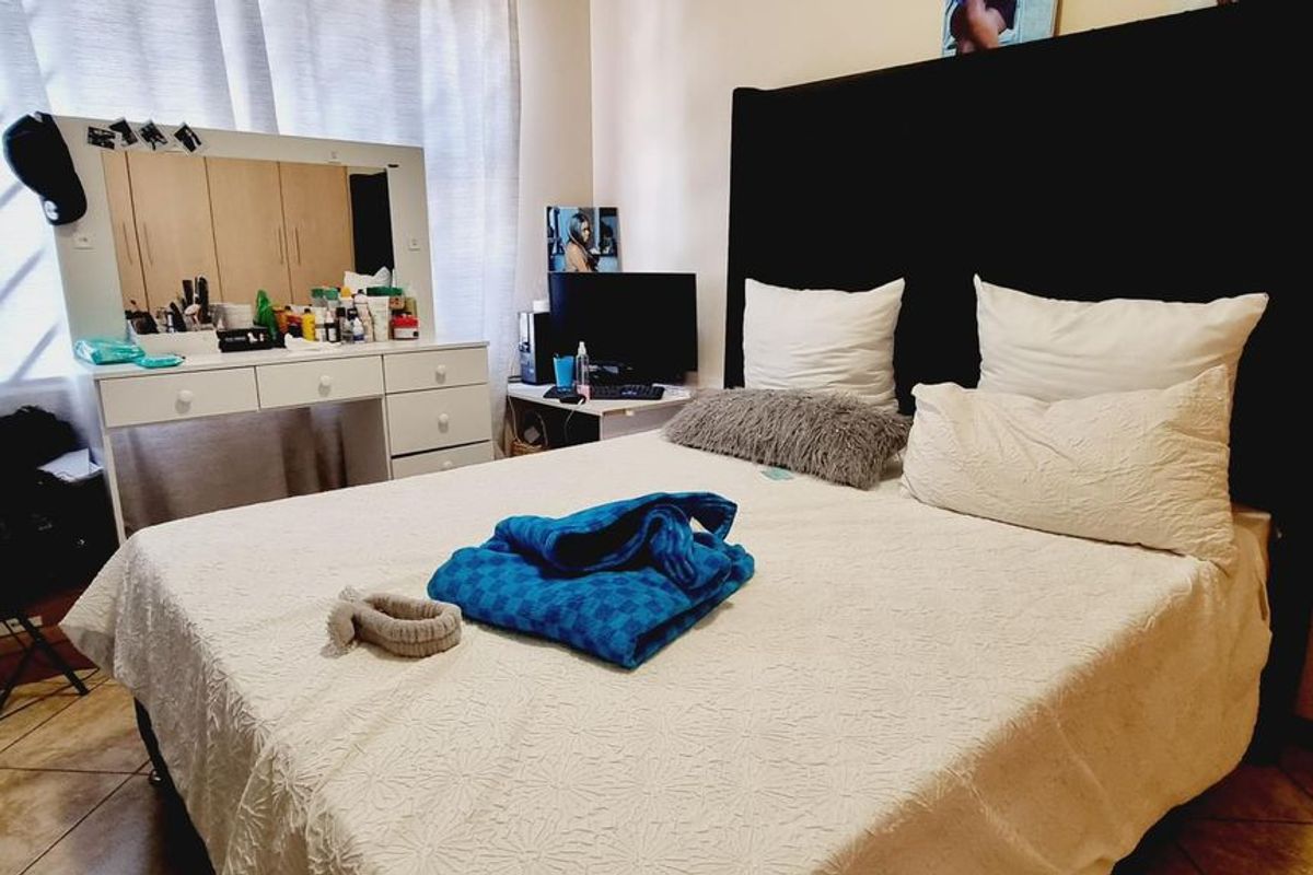 A bedroom featuring tiled flooring and built-in cupboard storage, offering a functional space with neutral wall finishes.