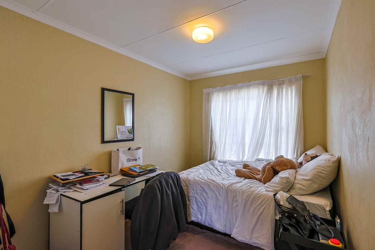 A functional bedroom featuring a window with curtain tracks and a central ceiling light fixture.