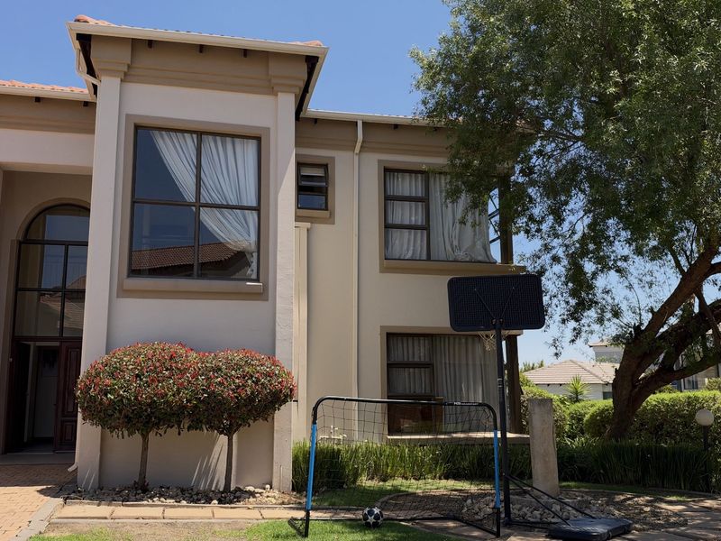 A well-maintained double-storey residential facade featuring a paved driveway, tiled roof, and modern aluminium window frames.