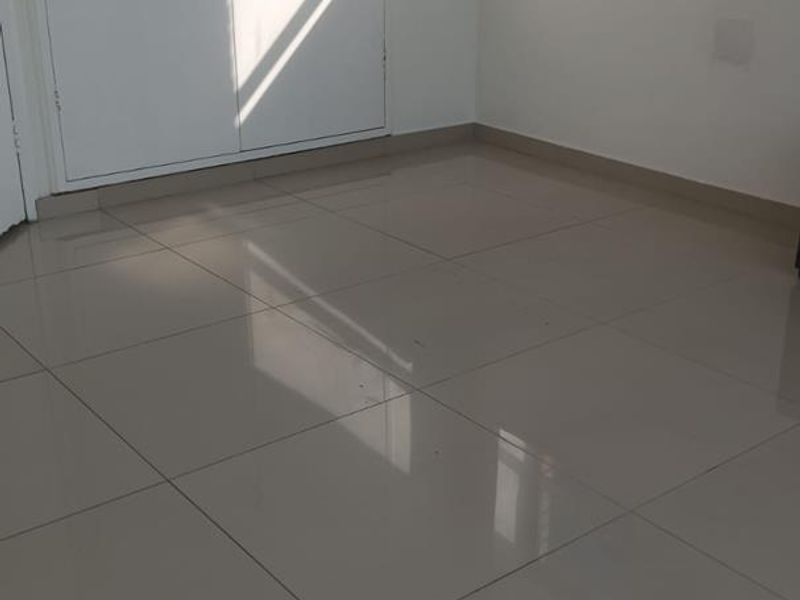 A bright, empty bedroom featuring neutral tiled flooring and built-in cupboards, offering a clean and versatile space ready for personalization.