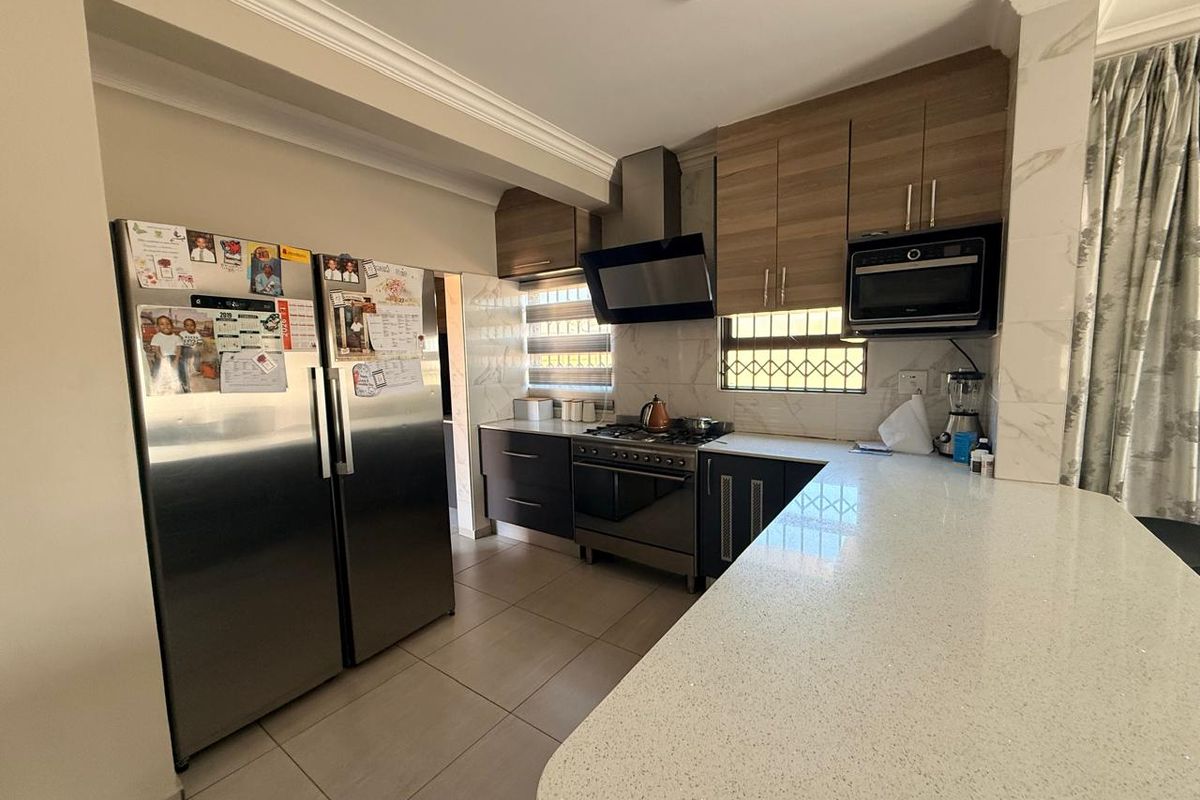 Modern kitchen featuring stone countertops, wood-finish cabinetry, a stainless steel gas stove with extractor fan, and a built-in microwave.