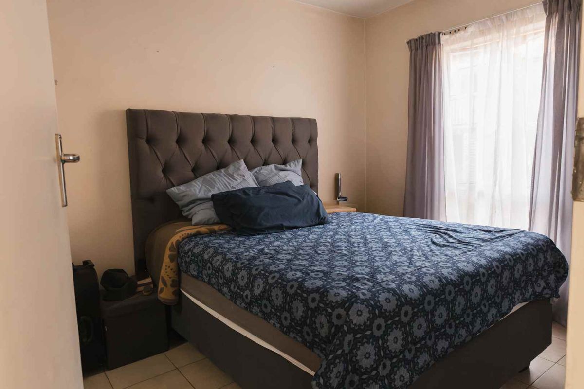 A standard bedroom featuring tiled flooring and a window with curtain tracks, providing a functional and neutral living space.