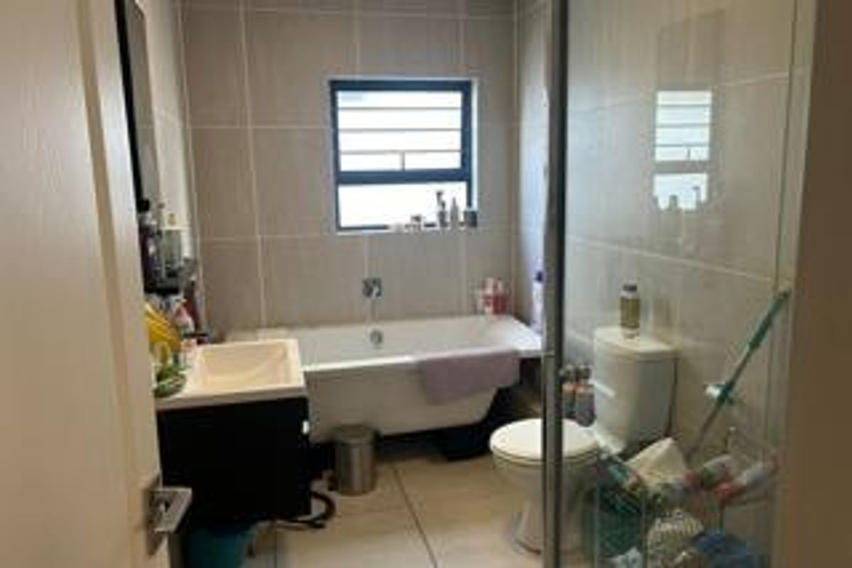 A functional bathroom featuring a bathtub, a vanity with a basin, a toilet, and tiled walls and flooring.