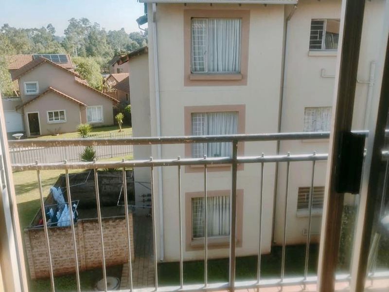 A balcony with tiled flooring and a metal balustrade, offering an elevated view of the surrounding residential complex and neighborhood.
