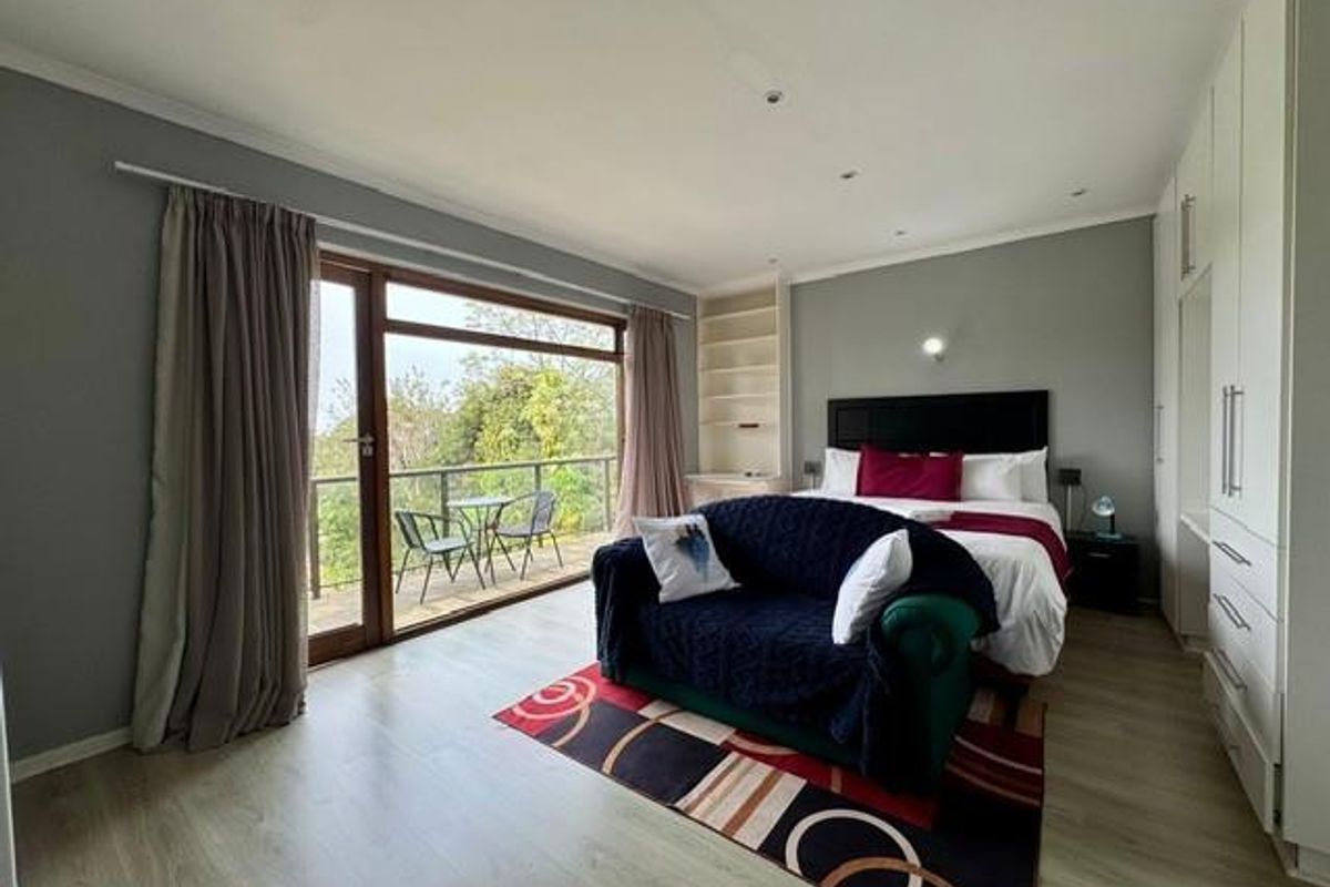Spacious bedroom featuring built-in floor-to-ceiling cabinetry, recessed lighting, and large sliding glass doors opening onto a private balcony with scenic views.