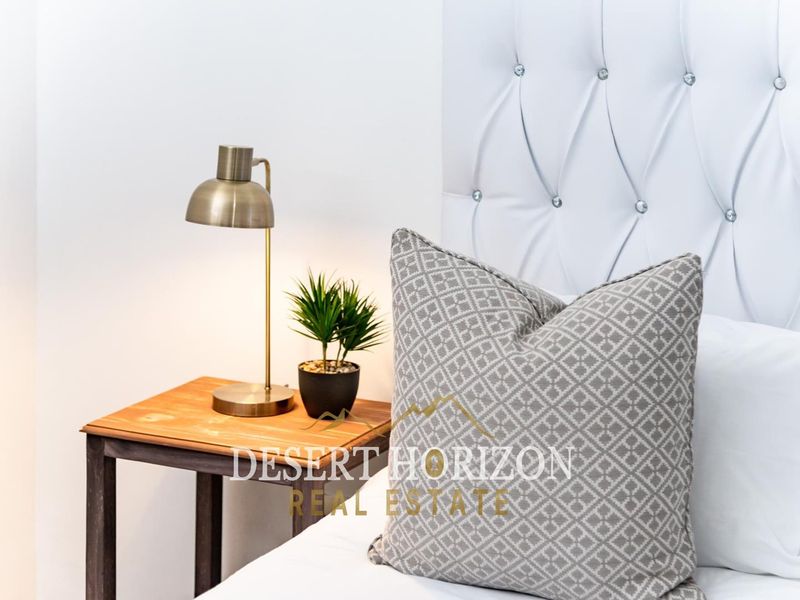 Close-up view of a bedroom featuring a white tufted headboard with decorative crystal buttons.