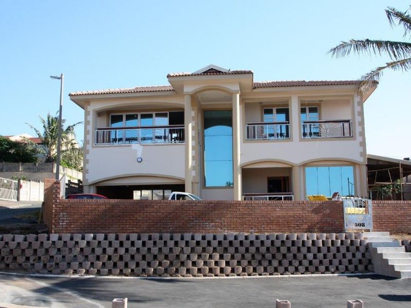 Front elevation of a multi-story residential property featuring a brick retaining wall, concrete stairs, and upper-level balconies with glass windows.