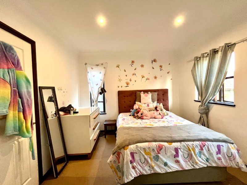A well-lit bedroom featuring neutral walls, carpeted flooring, and recessed downlighting, offering a comfortable and functional living space.