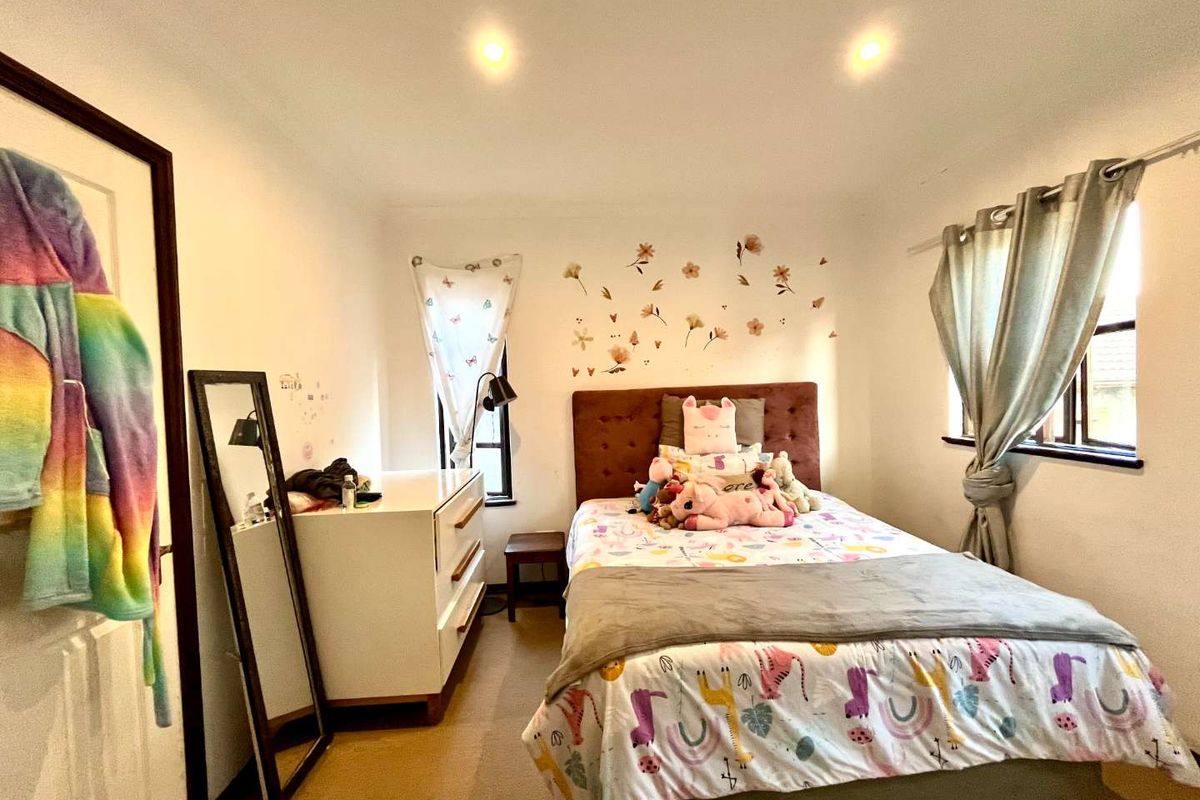 A well-lit bedroom featuring neutral walls, carpeted flooring, and recessed downlighting, offering a comfortable and functional living space.