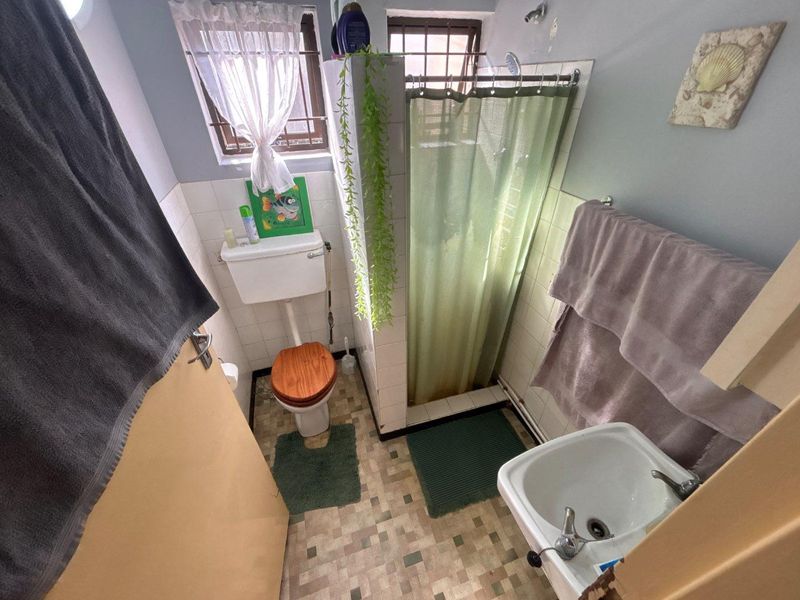 Compact bathroom featuring a shower, toilet, and basin with dated finishes and visible wear, offering potential for a modern renovation.