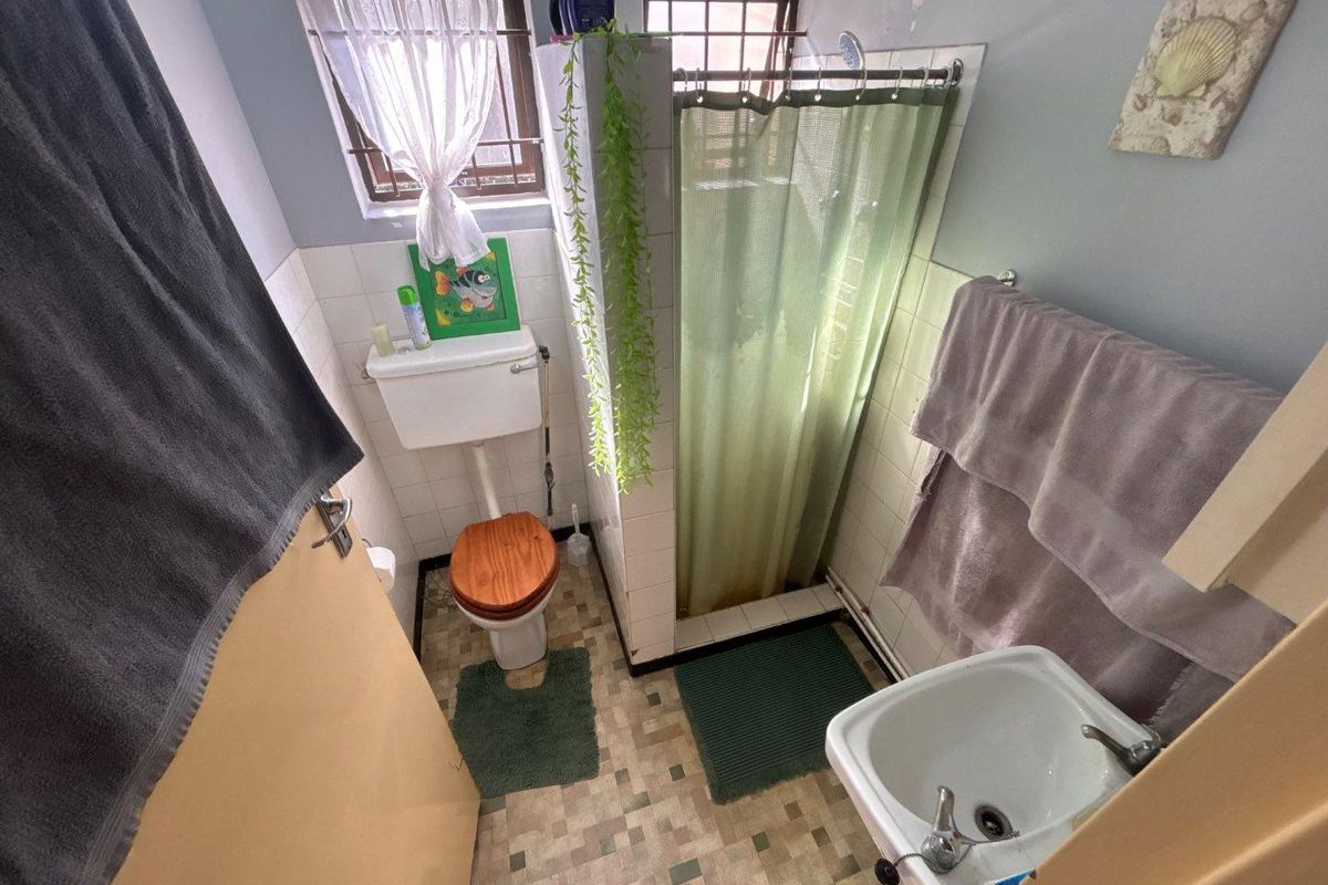 Compact bathroom featuring a shower, toilet, and basin with dated finishes and visible wear, offering potential for a modern renovation.