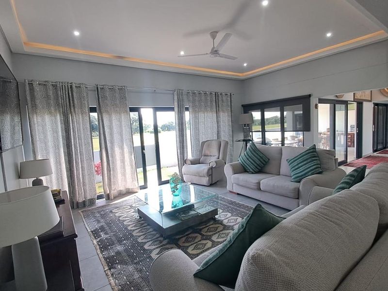Spacious living room featuring recessed ceiling lighting, cove lighting, a ceiling fan, and large sliding glass doors that provide natural light and outdoor access.