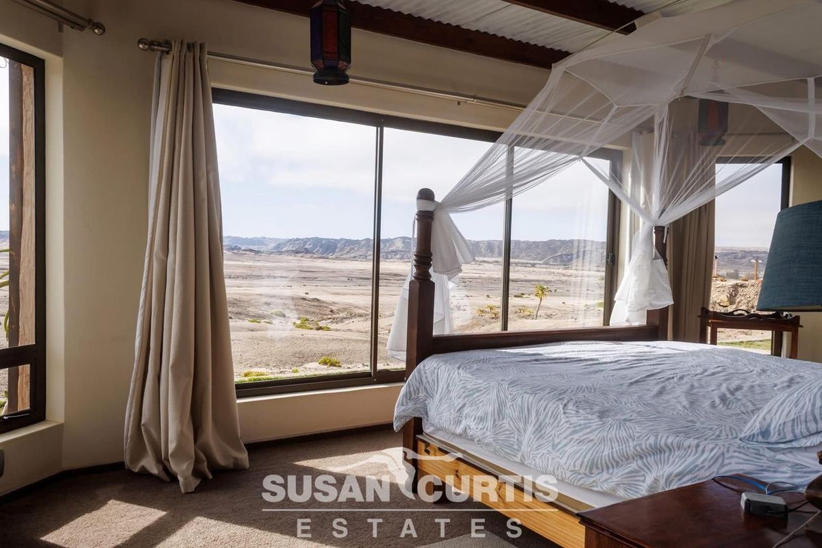 A spacious bedroom featuring large sliding glass doors that offer expansive, panoramic views of the surrounding arid landscape.