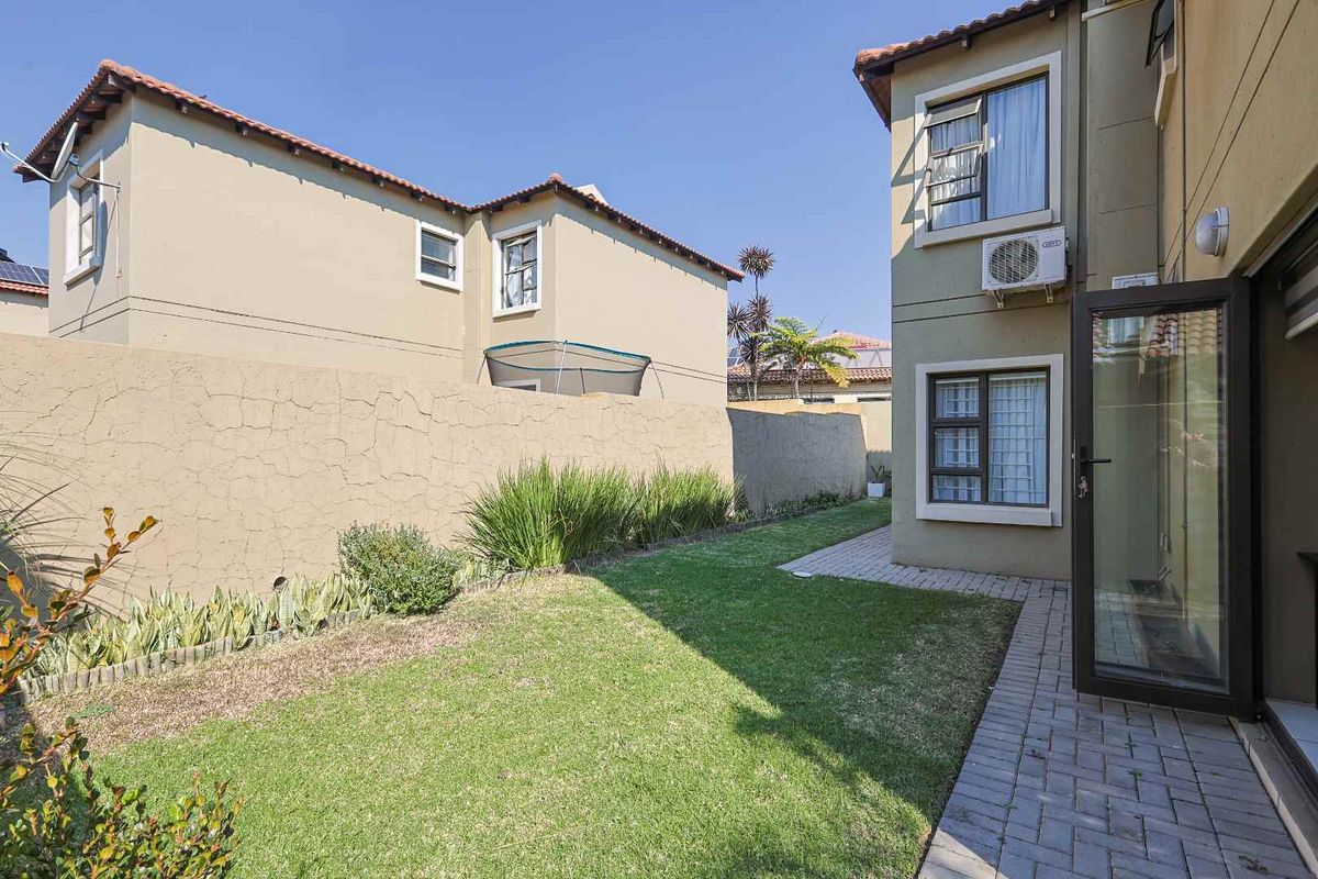 A private rear garden featuring a small lawn, paved walkway, and boundary wall, providing a functional outdoor space for the property.