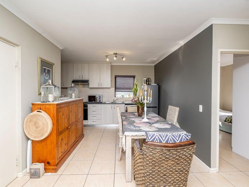 Open-plan kitchen and dining area featuring neutral cabinetry, tiled flooring, and a modern accent wall, providing a functional and well-lit living space.