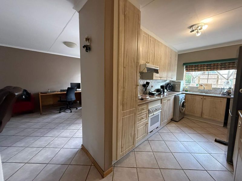 Open plan kitchen and adjacent living area featuring light wood cabinetry, tiled flooring, and functional built-in appliances.