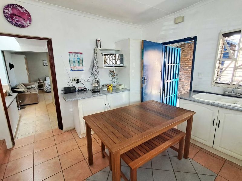 Functional kitchen area featuring built-in cabinetry, laminate countertops, double basin sink, and direct access to an exterior security gate.