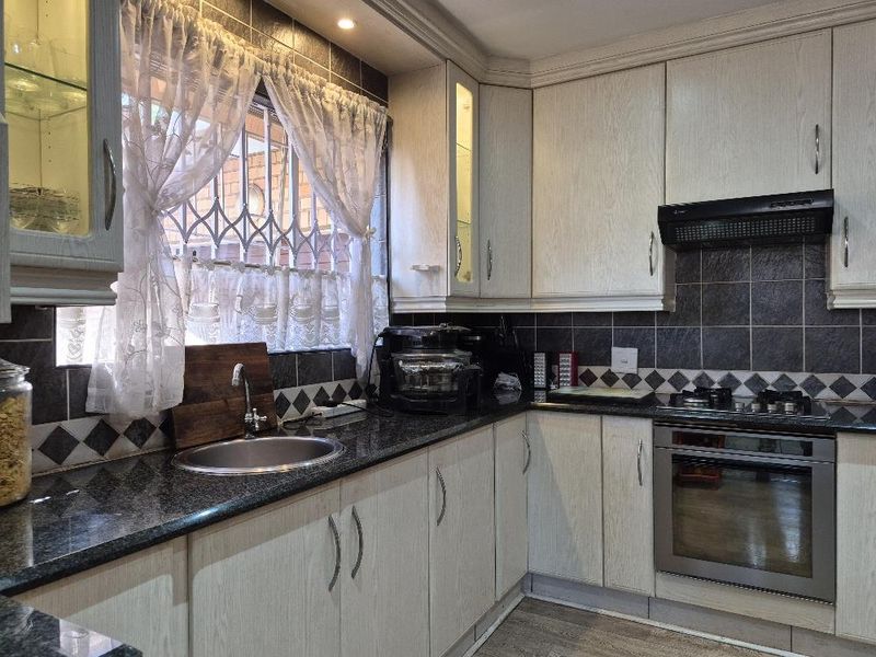 A functional kitchen featuring granite countertops, light-toned cabinetry, a built-in oven with gas hob, and a tiled backsplash.