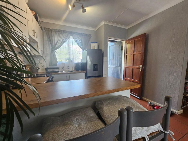 A functional kitchen featuring built-in cabinetry, a breakfast bar, and tiled flooring, with direct access to an exterior doorway.
